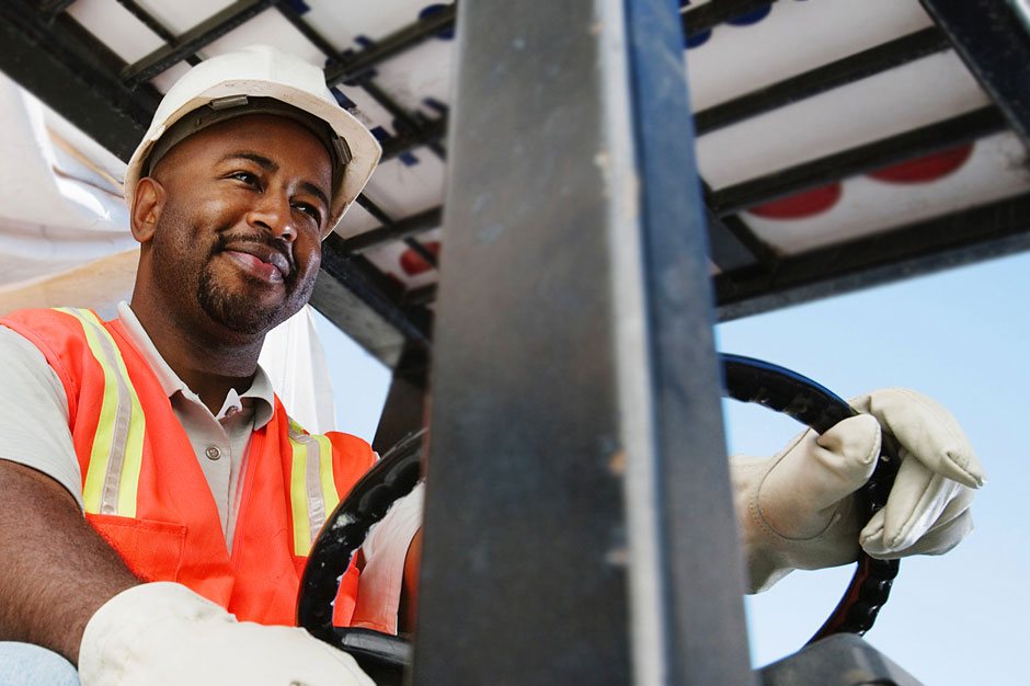 Happy forklift driver in manufacturing factory